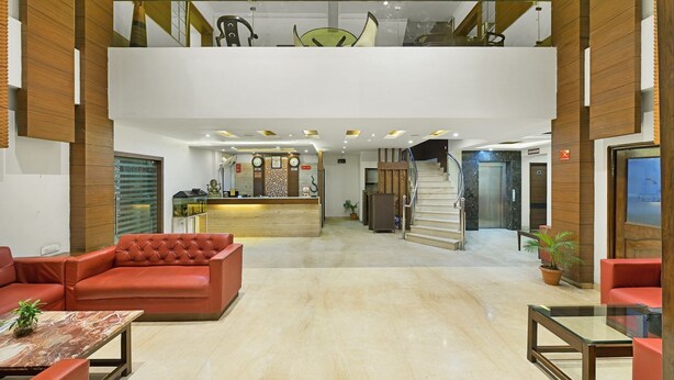 A hotel lobby with a reception desk, a staircase, and seating areas. - Hotel Paras (Dera Bassi)