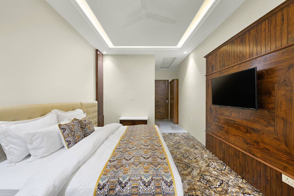 Un dormitorio con cama, televisor montado en la pared y ventilador de techo.