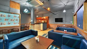 A restaurant with blue leather booths, a bar area, and a patterned wall. - Hotel Paras (Dera Bassi)