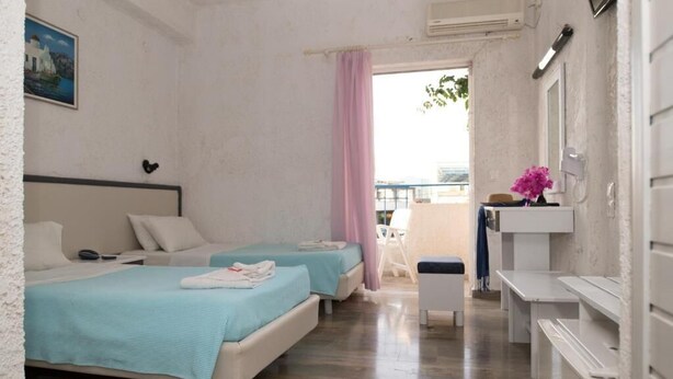 A room with two beds, a small balcony, a white sink, and a painting on the wall. - Gorgona Hotel (Malevizi)