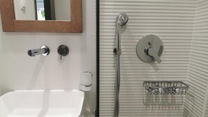 A bathroom with a white sink, a handheld showerhead, and a towel rack. - Gorgona Hotel (Malevizi)