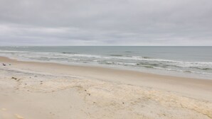 Une plage avec un rivage sablonneux et des vagues douces sous un ciel nuageux.