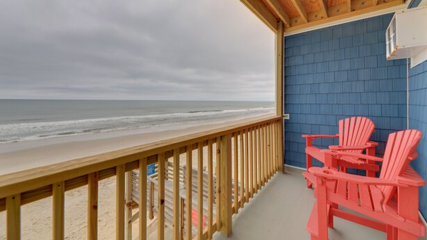 Une terrasse en bois offrant une vue sur la plage et l’océan.
