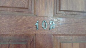 Una porta de fusta amb el número 102 gravat.