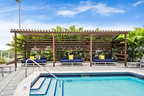Relax by the serene pool surrounded by a shaded pergola and comfortable lounge chairs.
