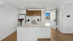 Una cocina moderna con armarios blancos, encimera de mármol y vistas al exterior.