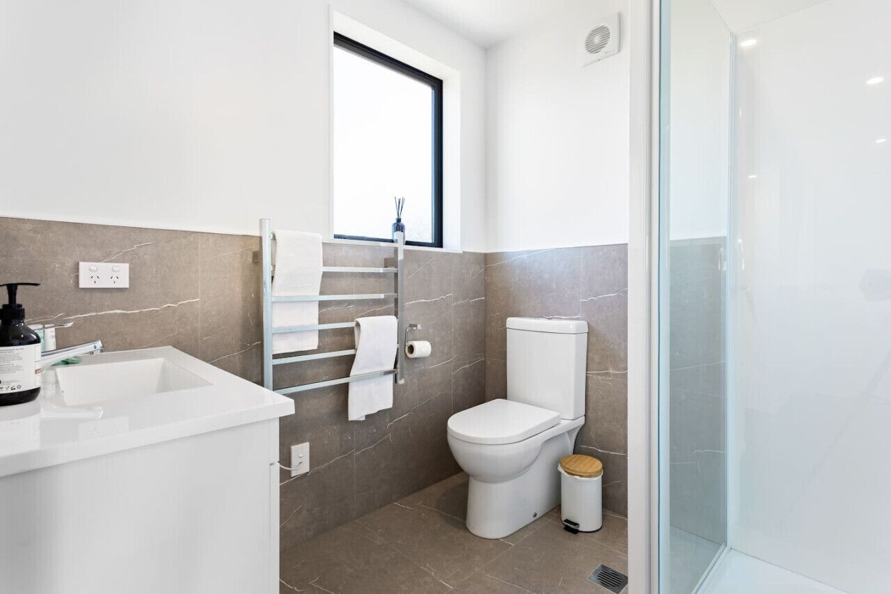 A modern bathroom with a white sink, toilet, and glass shower enclosure.