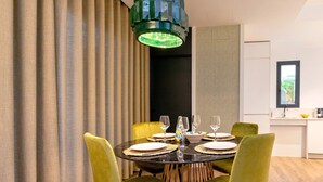 Un coin repas avec une table ronde, des chaises vertes et un lustre moderne.