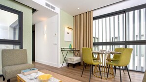 A modern living room with a sofa, a dining table with chairs, a coffee table, and a large window with curtains. - Genteel Home Betis XXII (Seville)
