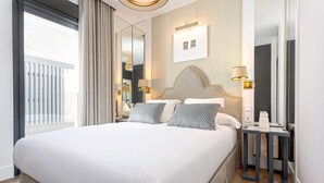 Ein Hotelzimmer mit einem großen Bett, einem Nachttisch mit Lampe, einem Spiegel und einem Bild an der Wand.