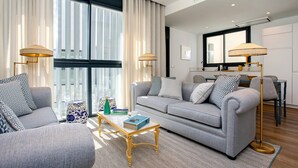 Ein modernes Wohnzimmer mit einem grauen Sofa, zwei Sesseln, einem Couchtisch und zwei Stehlampen.