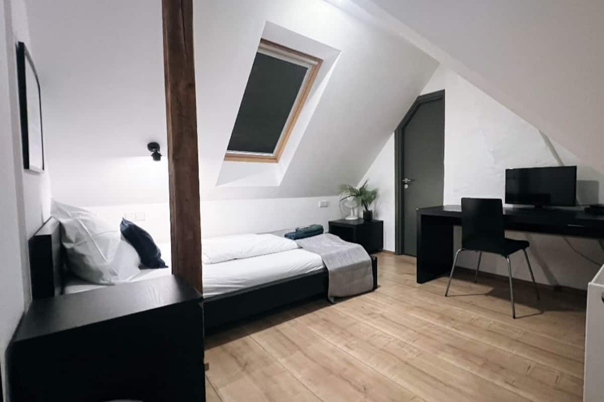 Quarto compacto e moderno com cama estilo loft, uma escrivaninha e uma cadeira.