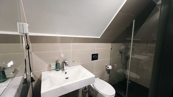A modern bathroom with a white sink, toilet, and glass shower enclosure. - Rheinländer Seehotel (Leverkusen)