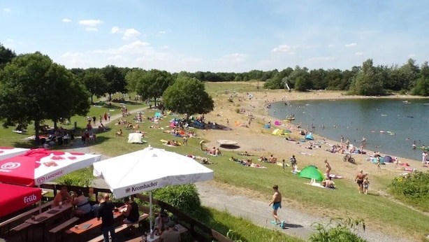 Järvenrantapuisto, jossa on piknikalueita, telttailumahdollisuuksia ja ihmisiä nauttimassa ulkoilmasta.