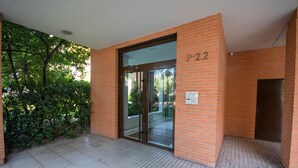 A building entrance with a glass door, brick walls, and a tiled floor.