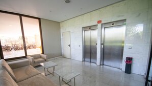 A lobby with a sofa, two tables, and two elevators.