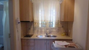 Una cocina compacta con armarios de madera, un lavamanos de acero inoxidable y una pequeña encimera.