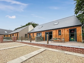 A building with a wooden exterior, a stone wall, and a gravel courtyard.