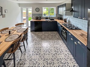 A modern kitchen with dark cabinets, a wooden countertop, and a patterned tile floor.