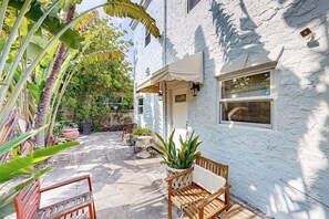 A white building with a patio area, outdoor seating, and potted plants.