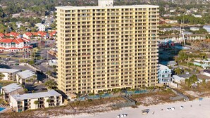 A high-rise hotel with multiple balconies, a pool area, and a beach view.