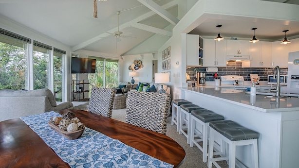 A spacious living area with a large wooden dining table, a kitchen with a bar, and a ceiling fan. - Private Home, Marsh Front Gorgeous View 874 Fiddlers Ridge (Fripp Island)