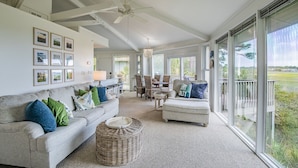 A spacious living room with a high ceiling, a ceiling fan, a large window, and a dining area with wicker furniture. - Private Home, Marsh Front Gorgeous View 874 Fiddlers Ridge (Fripp Island)