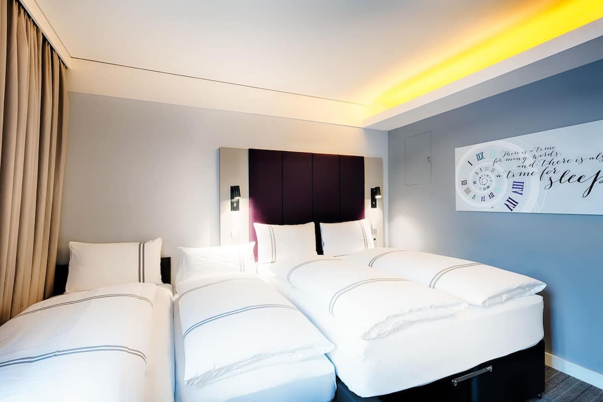 A hotel room with a large bed, two bedside tables, a headboard, and a wall clock.