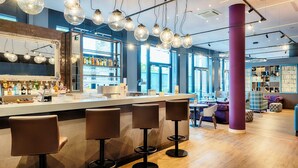A bar area with a counter, stools, and hanging lights. - Premier Inn Heilbronn City Centre (Heilbronn)