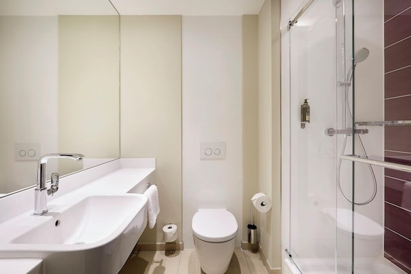 A modern bathroom with a bathtub, two sinks, a toilet, and a glass-enclosed shower. - Premier Inn Heilbronn City Centre (Heilbronn)