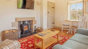 A cozy living room with a fireplace, a sofa, a coffee table, and a window with a view of the outdoors.