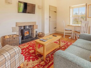 A cozy living room with a fireplace, a sofa, a coffee table, and a window with a view of the outdoors.