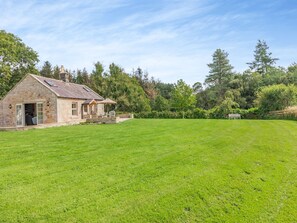 A stone house with a patio and a large grassy yard. - 1 bedroom accommodation in Eglingham, near Alnwick (Eglingham, near Alnwick)