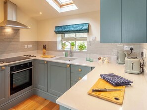A modern kitchen with grey cabinets, a built-in oven, a gas stove, and a window with a blue valance.