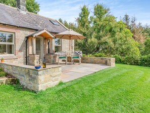 A stone house with a patio, outdoor seating, and a grassy lawn. - 1 bedroom accommodation in Eglingham, near Alnwick (Eglingham, near Alnwick)