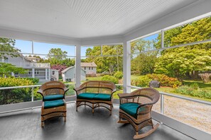 Relax in this serene sunroom with a view of the surrounding neighborhood, featuring a comfortable seating area and large glass enclosure.