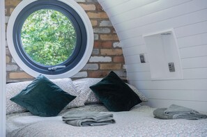 Une chambre avec une lucarne, un mur en briques et un plafond blanc.