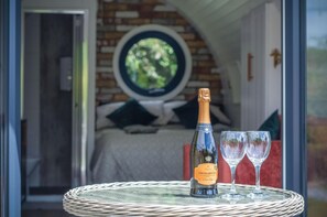 A bottle of Prio Riggio Italian sparkling wine and two glasses on a wicker table.