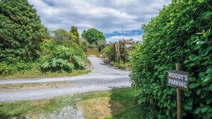 A gravel path leading to a wooden gate with a sign reading "WOODY'S PARKING". - Woody's - 1 Bedroom Pod - Cold Inn (Kilgetty)