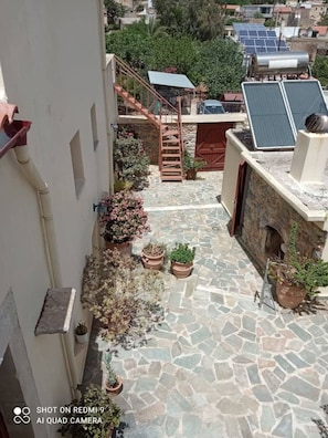Enjoy the serene rooftop retreat with a stone floor, surrounded by lush greenery and a staircase leading to an upper level.