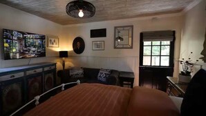 A cozy room with a bed, a sofa, a desk, and a window. - Carrington Cottage @ 420 Shiloh LGBTA Pet friendly Sanctuary with Soul (Palm Springs)