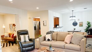 Una sala de estar con un sillón de cuero, un sofá color crema y una mesa de centro.