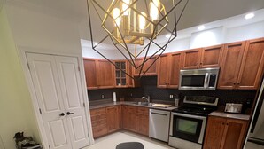 A modern kitchen with wooden cabinets, stainless steel appliances, and a glass dining table with black chairs.