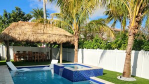 A swimming pool with a hot tub, surrounded by artificial grass and palm trees. - Private Beach Club, Heated Pool, Jacuzzi, & 6 Seater Golf Cart Included!  (Pompano Beach)