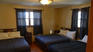 A room with three single beds, wooden floors, and a ceiling light fixture. - Spacious house with large yard in great location close to boat ramps. (Devils Lake)