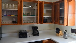 A kitchen with wooden cabinets, a coffee maker, and various kitchen utensils. - Spacious house with large yard in great location close to boat ramps. (Devils Lake)