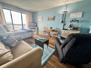 A living room with a sofa, a coffee table, a TV, and a dining area with a table and chairs.