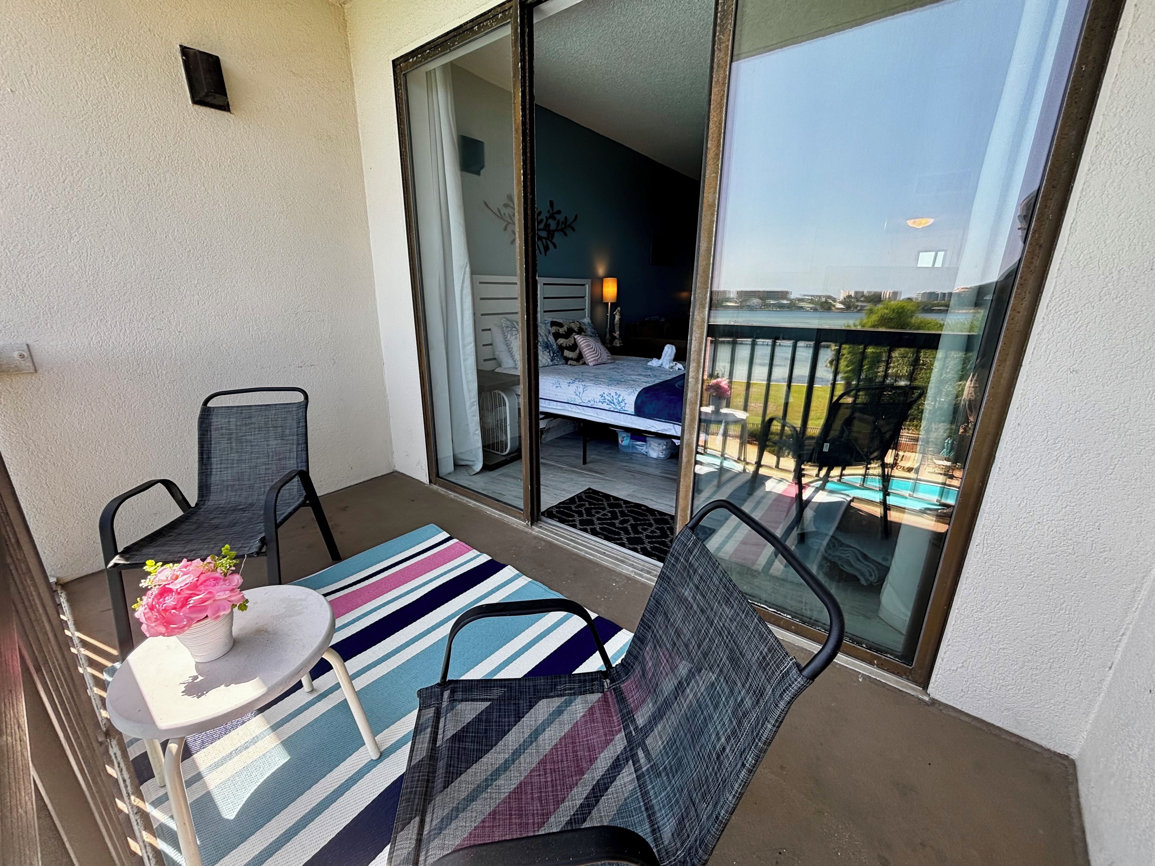 Un balcone con un letto, una sedia, un tavolino e un tappeto a righe.