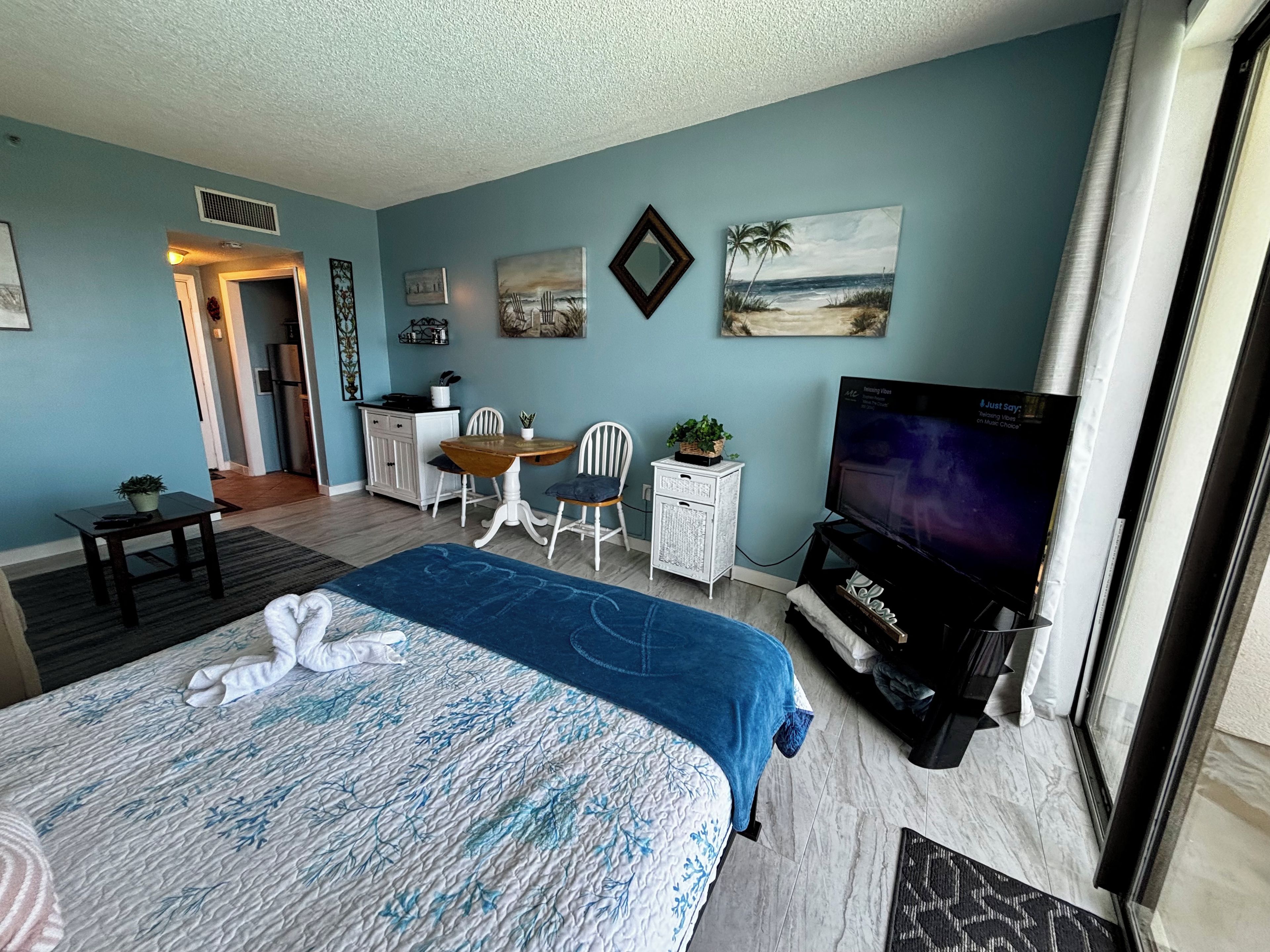 A hotel room with a bed, a desk, a chair, a television, and artwork on the walls.