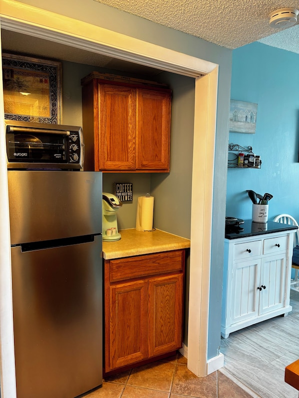 A compact kitchen with a built-in oven, a coffee maker, and wooden cabinets.
